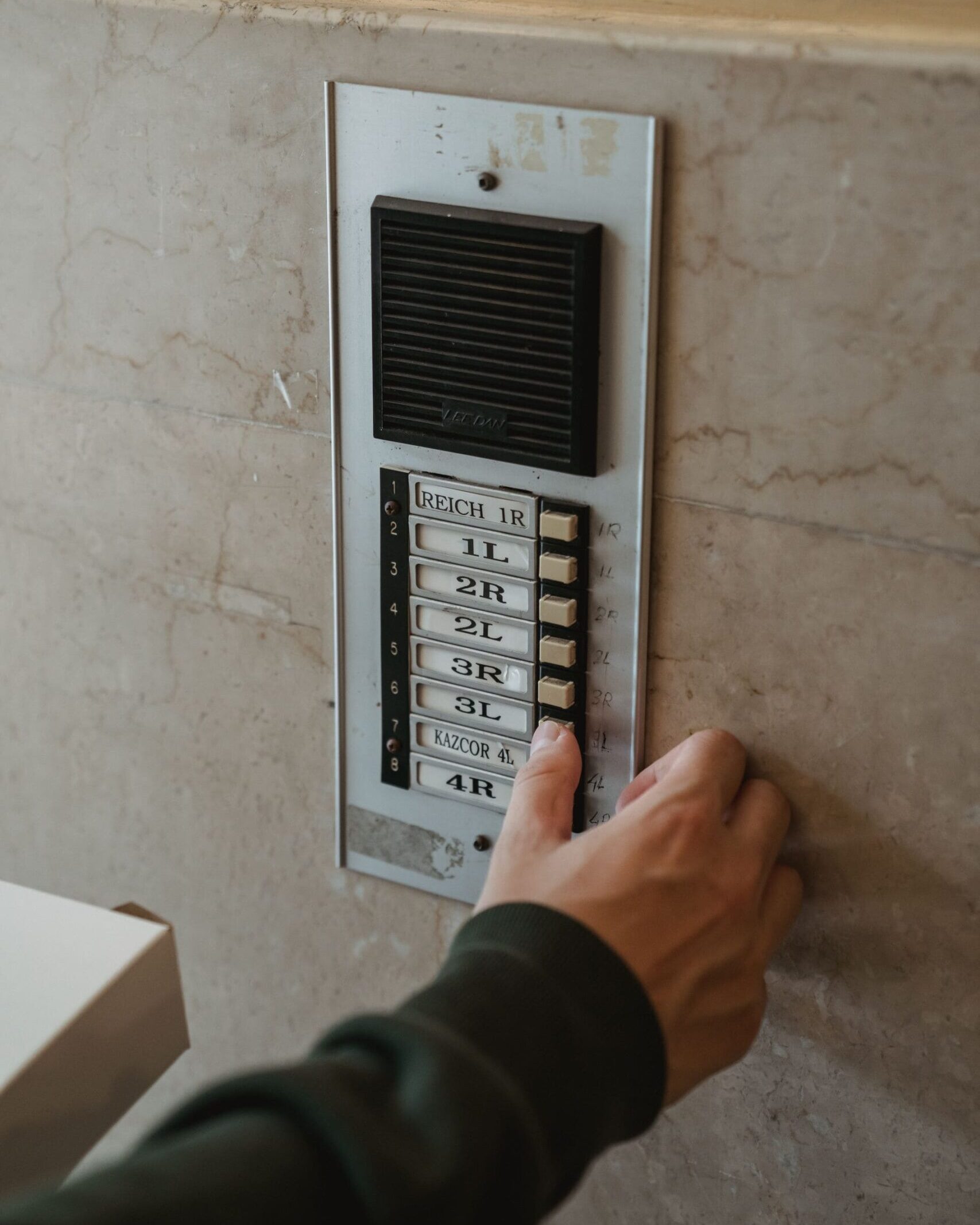 Addetto che utilizza un citofono condominiale durante un servizio di portierato.
